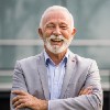 Smiling elderly man with crossed arms outdoors.