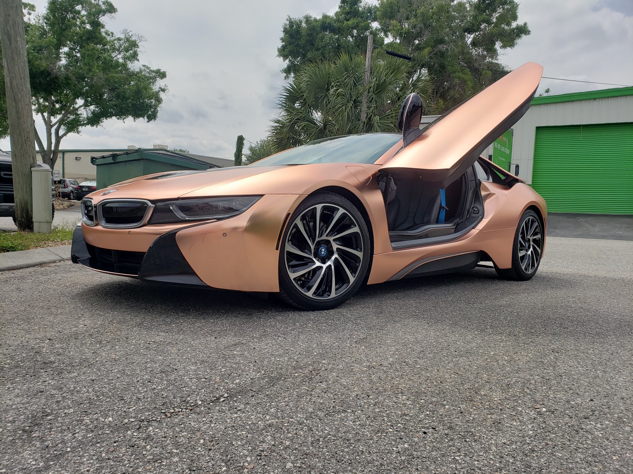 A sleek copper-colored sports car with butterfly doors open.