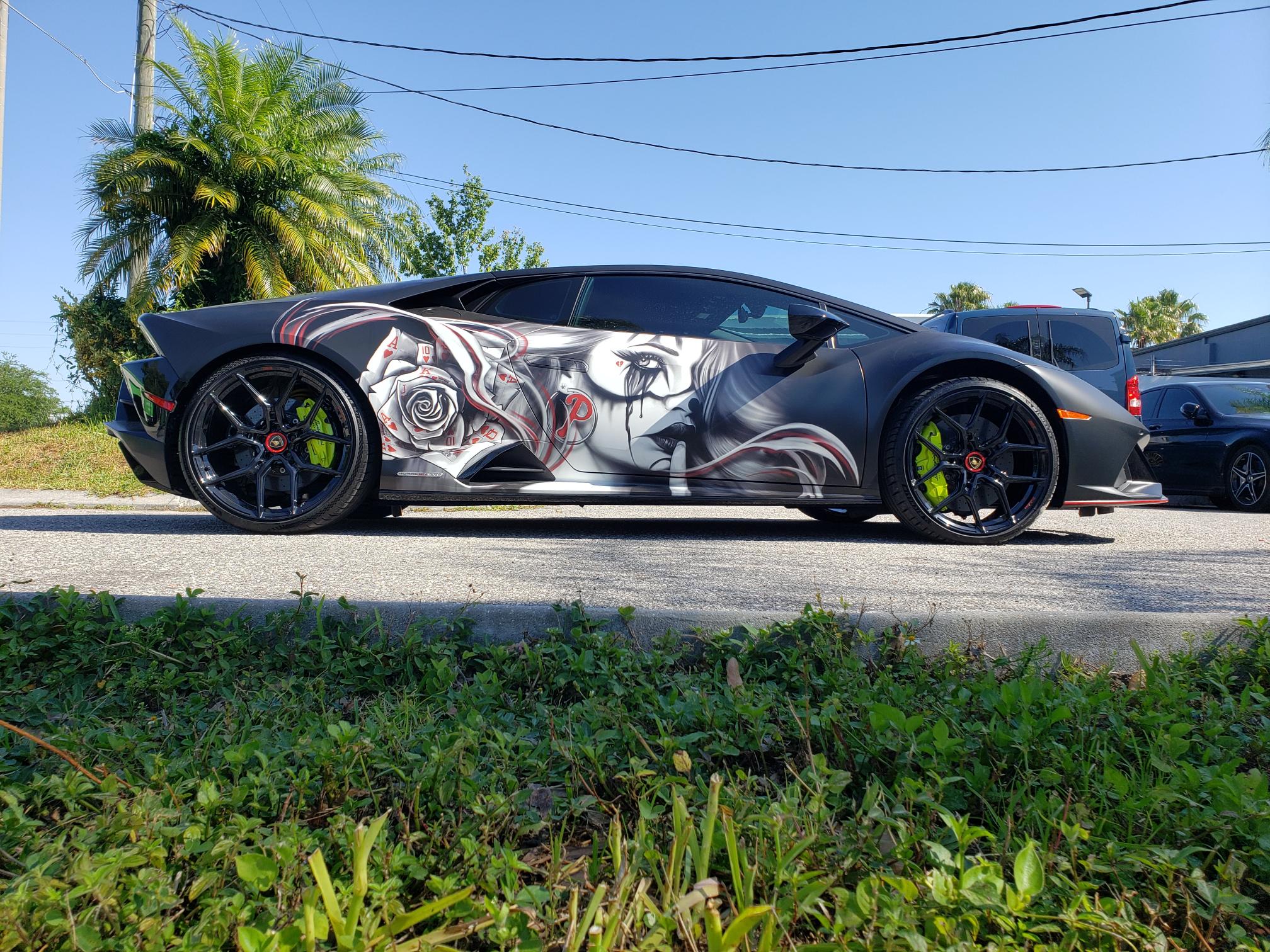 Sleek sports car with custom black and white graffiti-style artwork on its side.